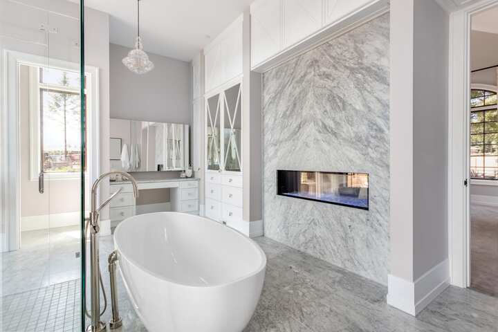 An elegant white marble bathtub installation with a fireplace sits in Westminster, Colorado mansion